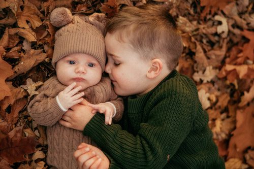 Heartwarming close-up of a boy gently kissing his younger sibling in an outdoor setting, photographed by a Canberra family photographer