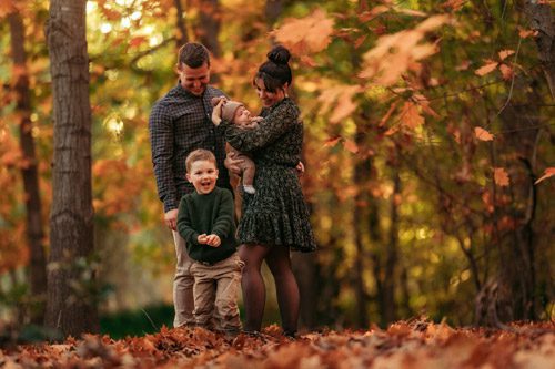 A family of four enjoys a peaceful moment together in a vibrant autumn forest, photographed by a winter Canberra family photographer