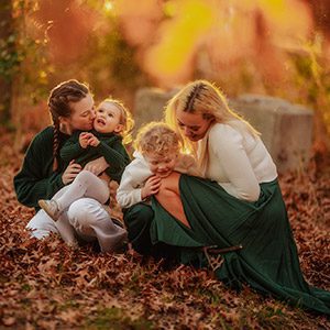 Joyful family photo of two young girls running through a lush green field in Canberra, with parents smiling in the background, captured during a spring family session